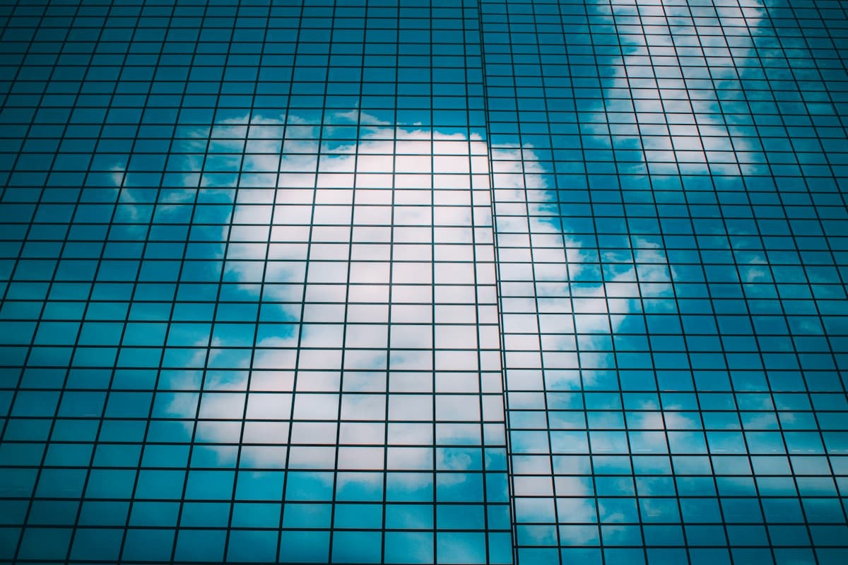 Glasfassade mit Wolkenspiegelung als Metapher für Cloud-Infrastruktur. Foto von sebastiaan stam auf Unsplash.